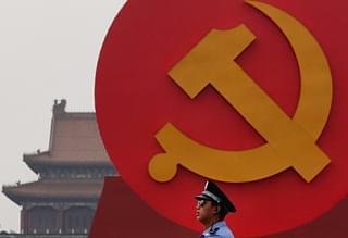 A policeman patrols under a giant communist emblem on the Tiananmen Square.(Photo by Feng Li/Getty Images)
