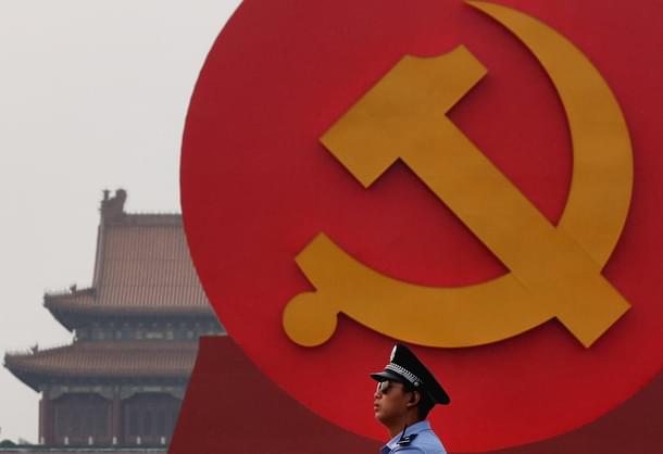 A policeman patrols under a giant communist emblem on the Tiananmen Square.(Photo by Feng Li/Getty Images)