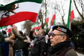 A man wearing an Iran beret stands with anti-regime protesters as they demonstrate outside the Iranian embassy in London, England. (Leon Neal/Getty Images)
