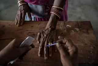 An Indian woman has her finger inked by an elections worker before voting at a polling station. (Kevin Frayer/Getty Images)