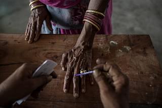 An Indian woman has her finger inked by an elections worker before voting at a polling station. (Kevin Frayer/Getty Images)