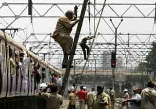 Railway workers repair overhead wire. (Satish Bate/Hindustan Times via Getty Images)