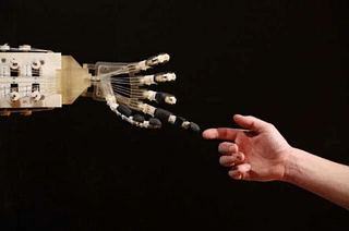 Robotics student Gildo Andreoni interacts with a Dexmart robotic hand built at the University of Bologna in the Robotville exhibition in London, England. (Oli Scarff/Getty Images)&nbsp;