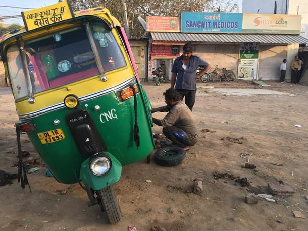Mukesh Jha (sitting) repairs an autorickshaw even as his shop (behind him in the frame) is sealed in a south Delhi market
