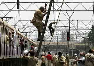 Railway workers repair overhead wire which was snapped between at between Khar and Santacruz. (Satish Bate/Hindustan Times via Getty Images)