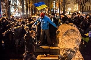 Protestors hammer a Lenin statue in Kiev as the Ukrainian flag is seen in the backdrop. (Brendan Hoffman via Getty Images)