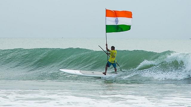 Murthy Megavan surfs holding the national flag