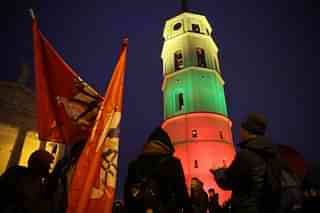 People dance next to the bell tower of Vilnius Cathedral as it stands illuminated in the colours of the Lithuanian flag to mark the 100th anniversary of the restoration of Lithuanian statehood in Vilnius, Lithuania. (Sean Gallup/Getty Images)