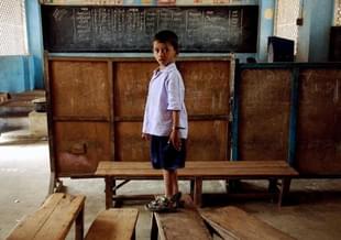 A government school student stands on a bench in his classroom. (SEBASTIAN D’SOUZA/AFP/GettyImages)