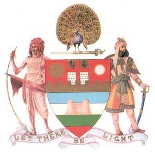 Mayo College Ajmer Coat of Arms with a Bhil Tribal and a Rajput holding a shield. (Wikimedia Commons)
