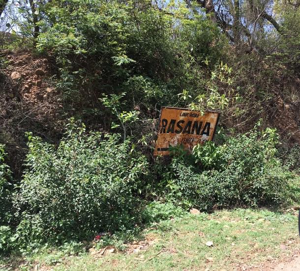 A battered iron board  announces the entry to Patta Rasana village