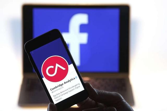 Cambridge Analytica’s Twitter page against the Facebook logo (Luke MacGregor/Bloomberg via Getty Images)