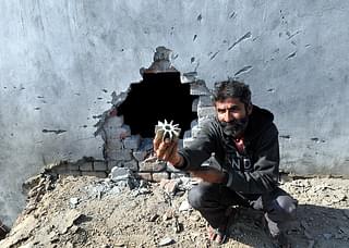 A villager showing a mortar shell found near the damaged wall of his house at Arnia sector, on 19 January 2018&nbsp;