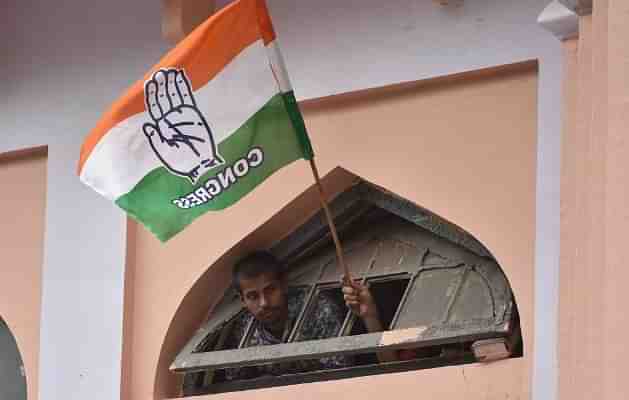 A Congress supporter waves the party flag during the road show of the All India Congress Committee president Rahul Gandhi in Bengaluru. (Arijit Sen/Hindustan Times via Getty Images)