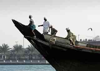 An Indian dhow crew straddles the bow of their boat December 14, 2005, in Dubai, United Arab Emirates. (Chris Jackson/Getty Images)