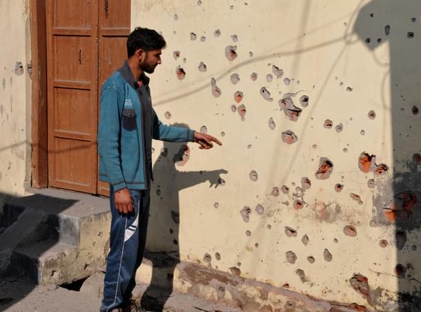 A villager points to the wall of a house damaged during firing at Arnia sector, on 19 January 2018