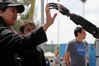 A woman reaches to touch a robotic arm developed by the Johns Hopkins University Applied Physics Laboratory, on display at an expo in California. (Chip Somodevilla/GettyImages)&nbsp;