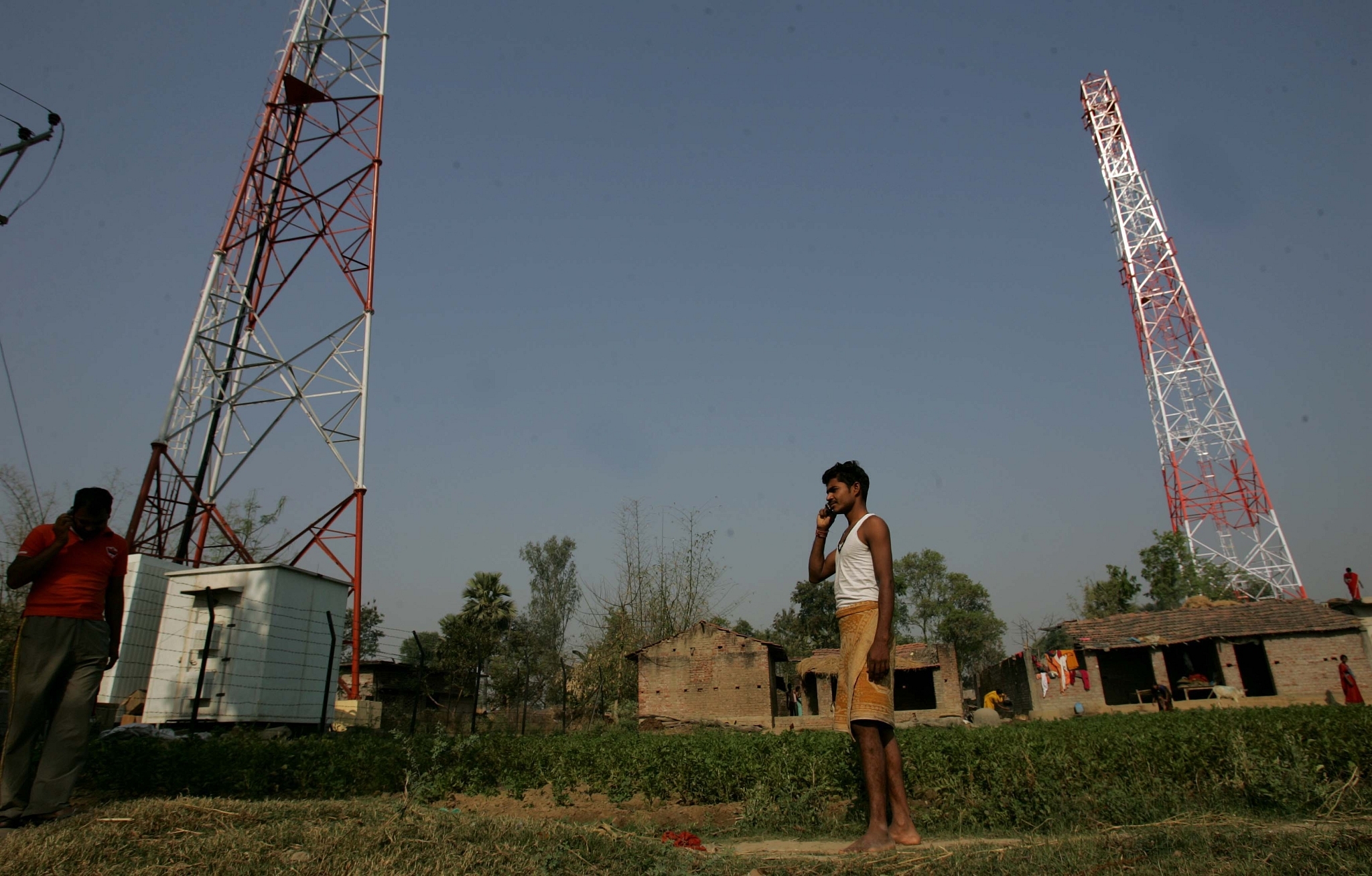 A man talks on the phone near telecom towers (Vijayanand Gupta/Hindustan Times via Getty Images)