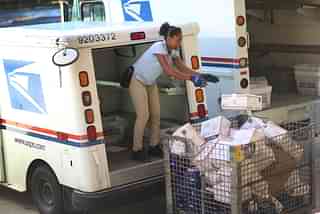 An employee of the United States Postal Service unloads a delivery van in Miami, Florida (Joe Raedle/Getty Images)