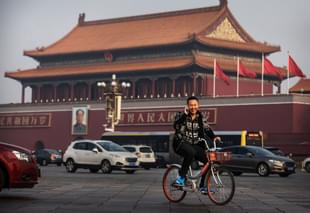 A Chinese man talks on his phone as he rides a bike through Tiananmen Square in Beijing. (Kevin Frayer/Getty Images) 