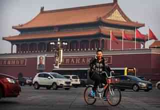 A Chinese man talks on his phone as he rides a bike through Tiananmen Square in Beijing. (Kevin Frayer/Getty Images)&nbsp;