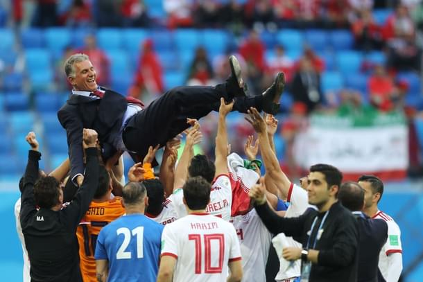 The Iranian team celebrates its victory with manager Carlos Quieroz. (Richard Heathcote/Getty Images)