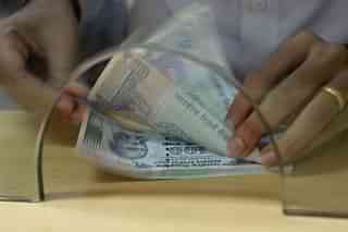 A customer counts Rs 100 currency notes after withdrawing money at a bank. (INDRANIL MUKHERJEE/AFP/Getty Images)