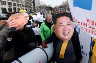 An activist with a mask of Kim Jong-un and another with a mask of Donald Trump march with a model of a nuclear rocket during a demonstration against nuclear weapons in Berlin, Germany. (Adam Berry/Getty Images) 