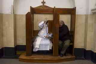 A priest administers the Catholic sacrament of confession to a man. (EITAN ABRAMOVICH/AFP/Getty Images)