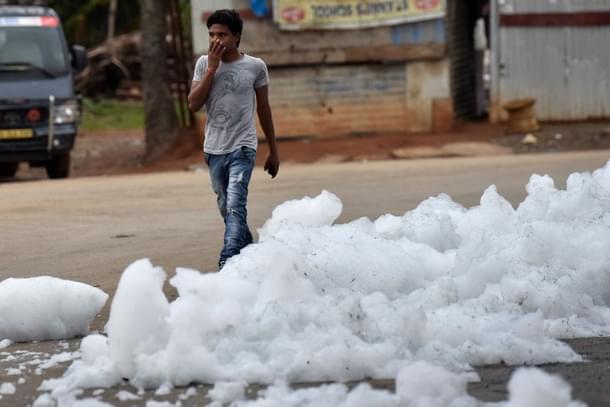 A youngster walks through flying froth from the polluted Bellandur Lake in Bengaluru. (Arijit Sen/Hindustan Times via GettyImages) 