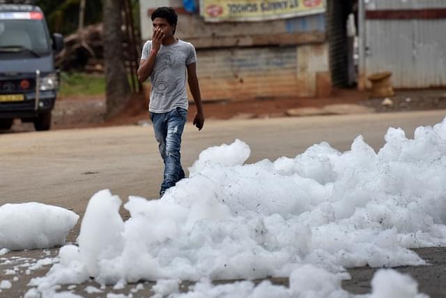 A youngster walks through  the flying froth from the polluted Bellandur Lake in Bengaluru. (Arijit Sen/Hindustan Times via GettyImages)&nbsp;