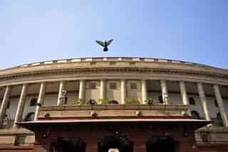 A pigeon flies over the Parliament building in New Delhi. (Vipin Kumar/Hindustan Times via Getty Images)