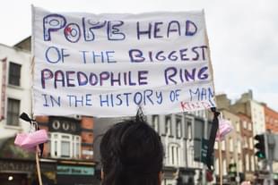 A protester holds up a sign in reference to the sex abuse scandal within the Catholic Church as Pope Francis travels. (Charles McQuillan/Getty Images)