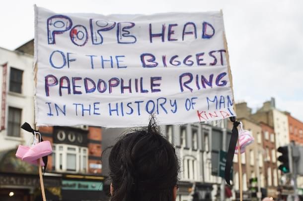 A protester holds up a sign in reference to the sex abuse scandal within the Catholic Church as Pope Francis travels. (Charles McQuillan/Getty Images)