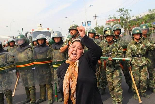 A protesting Uyghur woman surrounded by Chinese security personnel. (pic via Twitter)