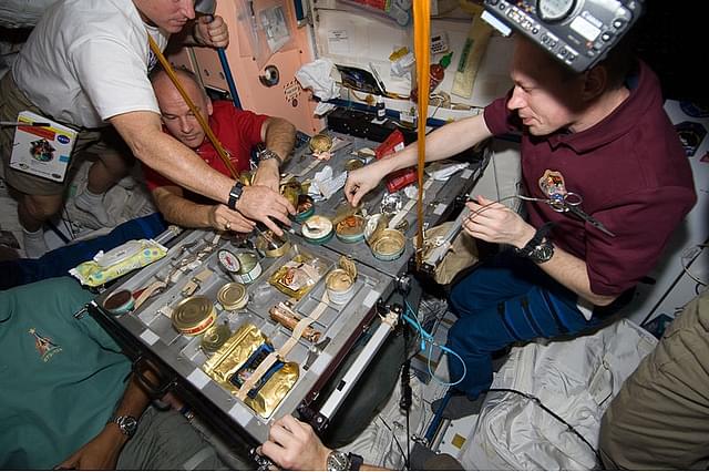 Crew members gather for a meal at the galley in the Unity node of the International Space Station. (Wikimedia Commons)