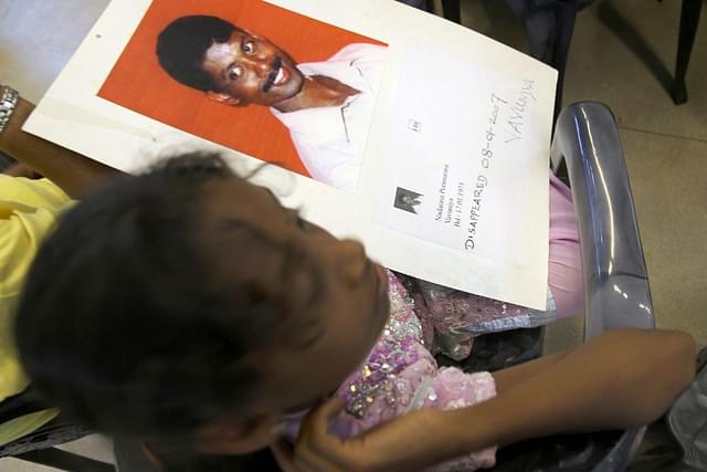 A Sri Lankan Tamil girl holds her father’s picture who disappeared during the final stage of the civil war in the country. (Buddhika Weerasinghe/Getty Images)