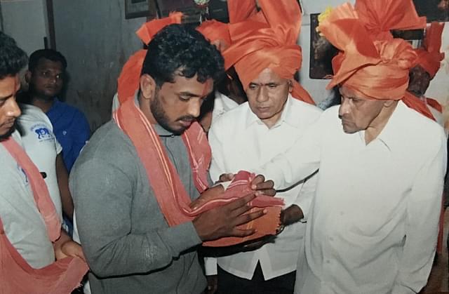 A victorious wrestler being felicitated by patrons and elders