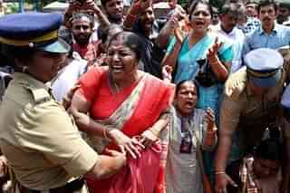 A woman devotee is being detained by a police officer during a protest called by various Hindu organisations in Sabarimala.