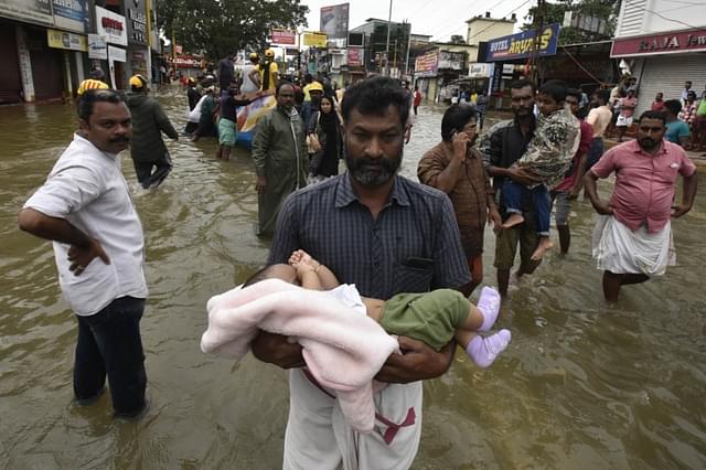 A man carrying a child through the flood water to a safe place at Panadala, on August 18, 2018 in district Pathanamthitta, Kerala. (Raj K Raj/Hindustan Times via Getty Images)