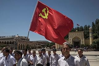 Ethnic Uyghur members of the Communist Party of China carry a flag (Photo by Kevin Frayer/Getty Images)