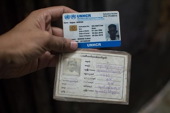 A Rohingya man in New Delhi holds up his refugee card issued by UNHCR. 