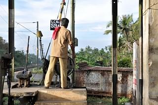A railway gatekeeper closes the gate at a level crossing. (Image- Joe Ravi via Wikimedia Commons)