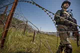 An Indian Army soldier patrols on the fence near the India-Pakistan LOC. (Gurinder Osan/Hindustan Times via Getty Images)