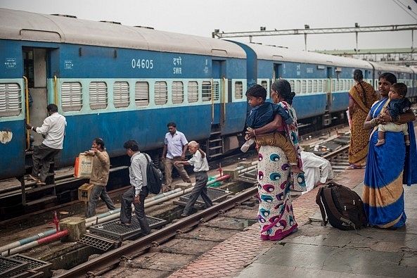 People rush to catch a train at a railway station (Photo by Brooke Herbert/Getty Images)