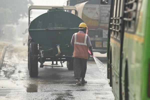 A worker sprinkles water roadside in a bid to bring down pollution from dust near Pragati Maidan on October 30, 2018 in New Delhi, India. (Raj K Raj/Hindustan Times via Getty Images)