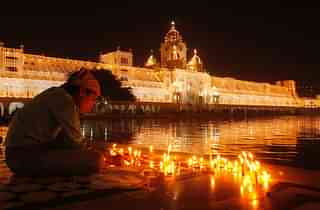 A devotee lighting the candles in Harmandar Sahib Complex (Munish Byala/Hindustan Times via Getty Images)