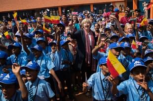British Prime Minister Theresa May waves a flag as she watches a flypast by the Indian Airforce with children at Stonehill Government Primary School on 8 November 2016 in Bangalore, India. (Dan Kitwood/Getty Images)