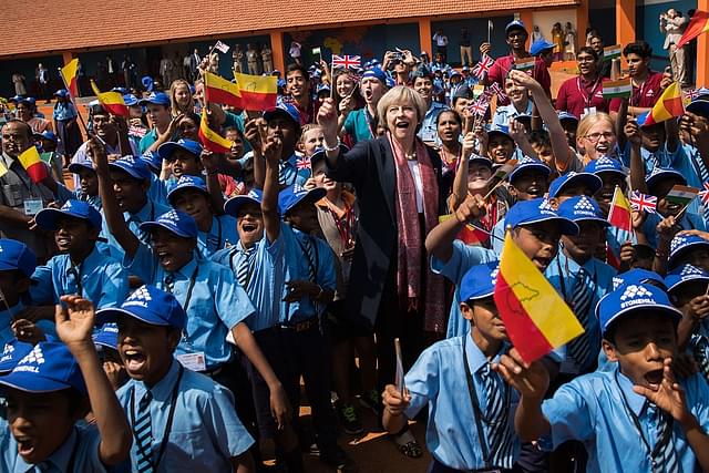  British Prime Minister Theresa May waves a flag as she watches a flypast by the Indian Airforce with children at Stonehill Government Primary School on 8 November 2016 in Bangalore, India. (Dan Kitwood/Getty Images)
