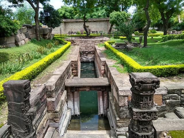 Pillars of baoli with Krishna leela scenes. Steps lead to a circular well
